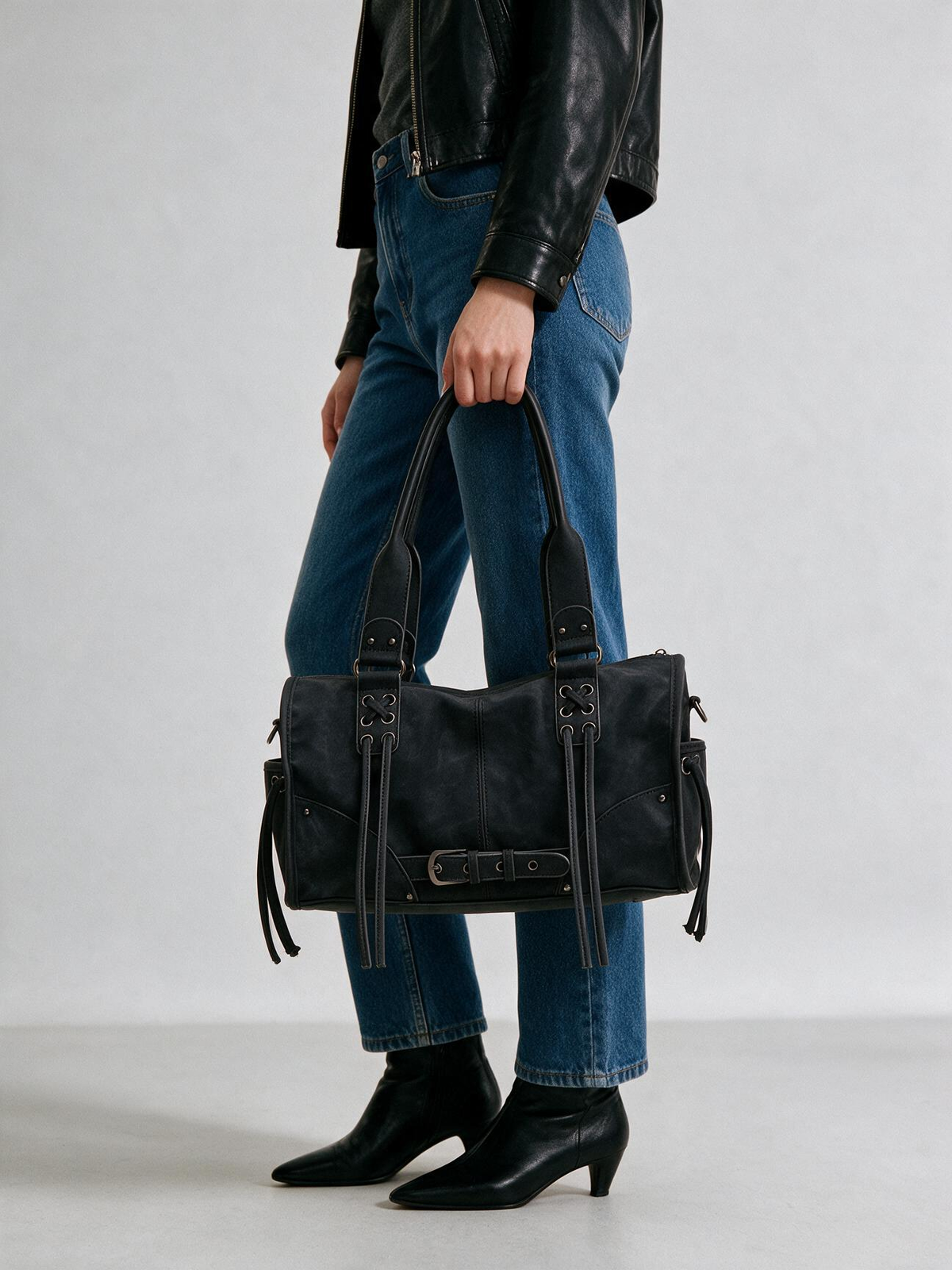 Woman styling the black satchel bag with a dark outfit