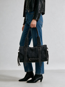 Woman styling the black satchel bag with a dark outfit