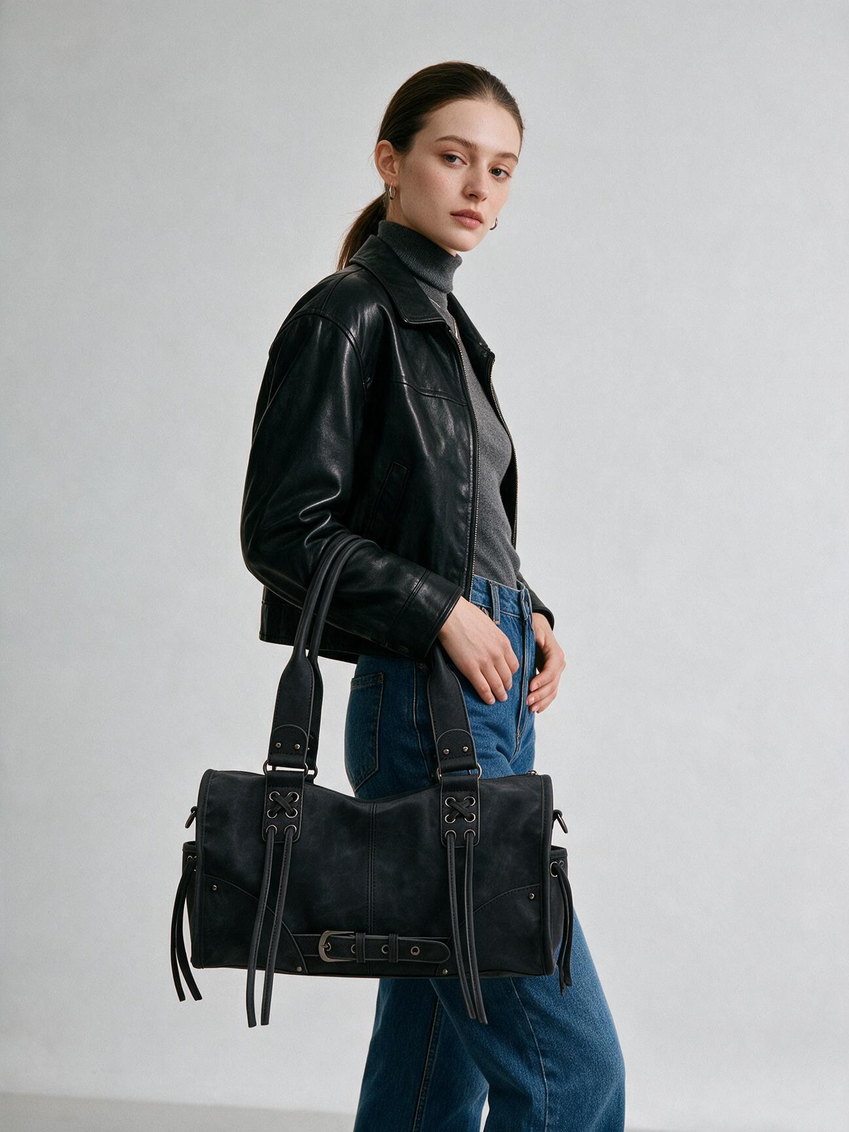 Side view of woman carrying the black crossbody satchel