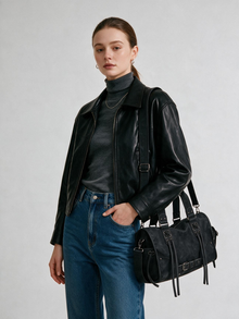 Woman carrying a black belted top handle satchel bag