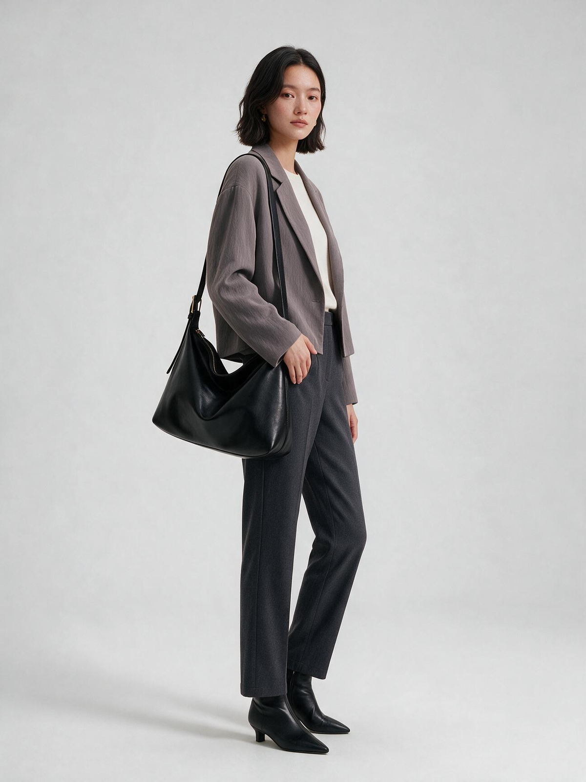 Woman carrying the black crossbody hobo bag with a gray blazer