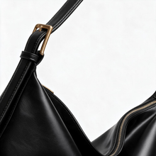 Close-up of black faux leather bag strap and gold-tone hardware