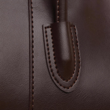 Close-up of stitching and handle attachment on brown faux leather tote