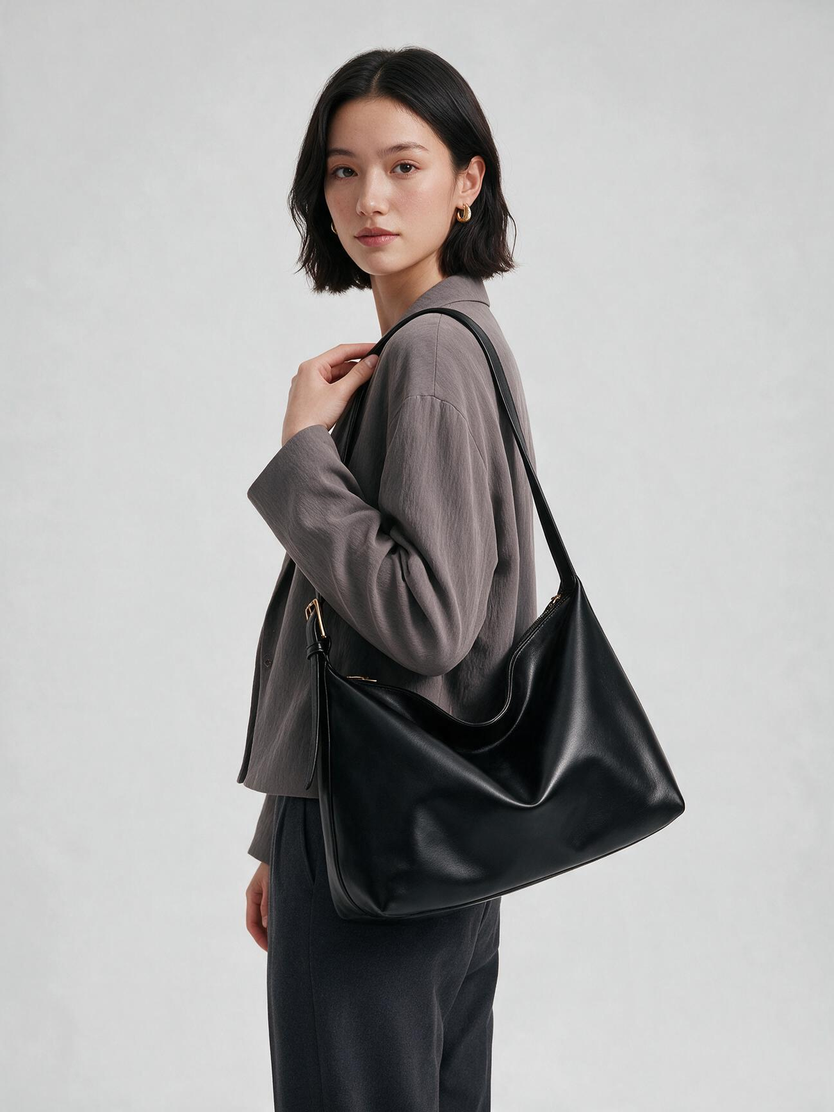 Woman wearing black hobo bag crossbody with a gray jacket