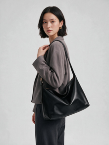 Woman wearing black hobo bag crossbody with a gray jacket