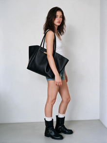 Model carrying the black winged tote bag by hand