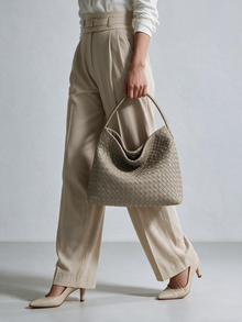 Model holding the taupe woven-look hobo bag by its short handle